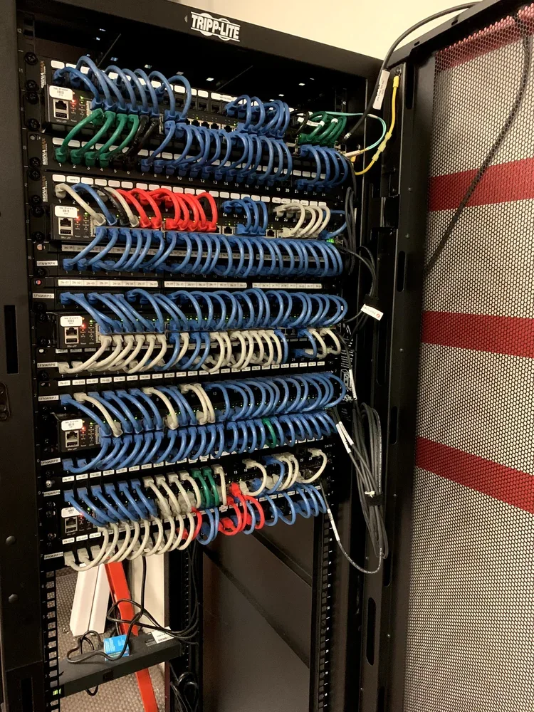 Enclosed cabinet with color-coded patch cables across several patch panels